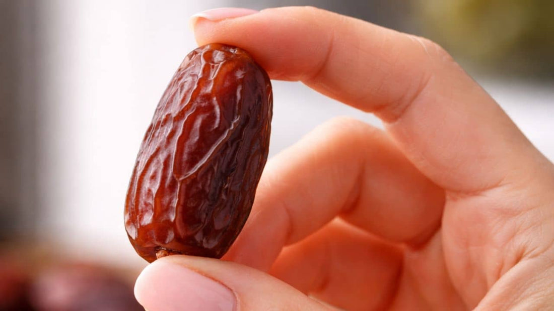 Main de femme tenant une datte Medjool fraîche, illustration de la conservation des dattes