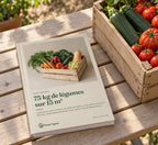 Ebook « 75 kg de légumes sur 15 m² » imprimé, posé sur une table de jardin à côté d’une cagette de tomates et de courgettes